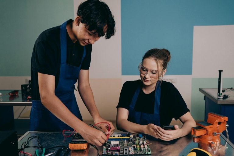 Two young engineers working on a circuit board together in a modern lab.